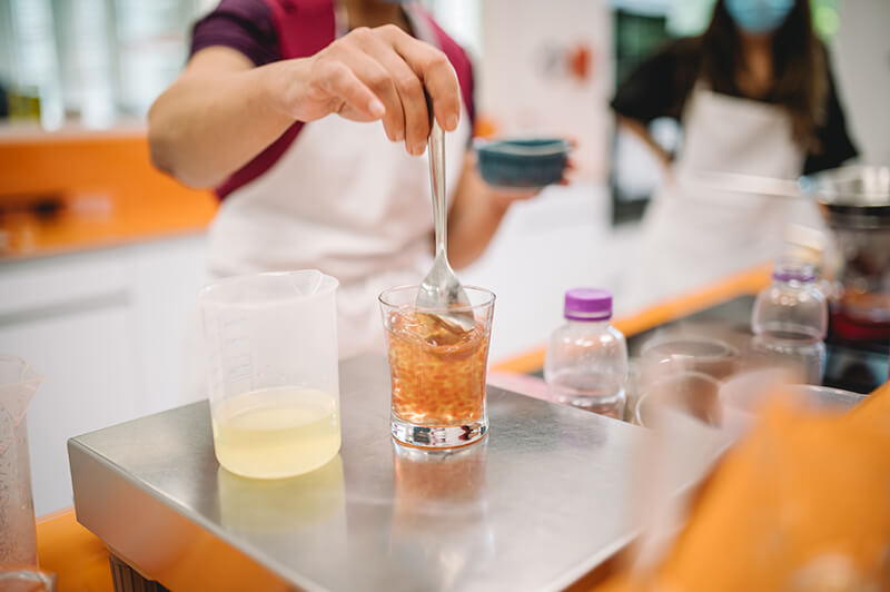 people in a kitchen lab stirring liquid with spoon